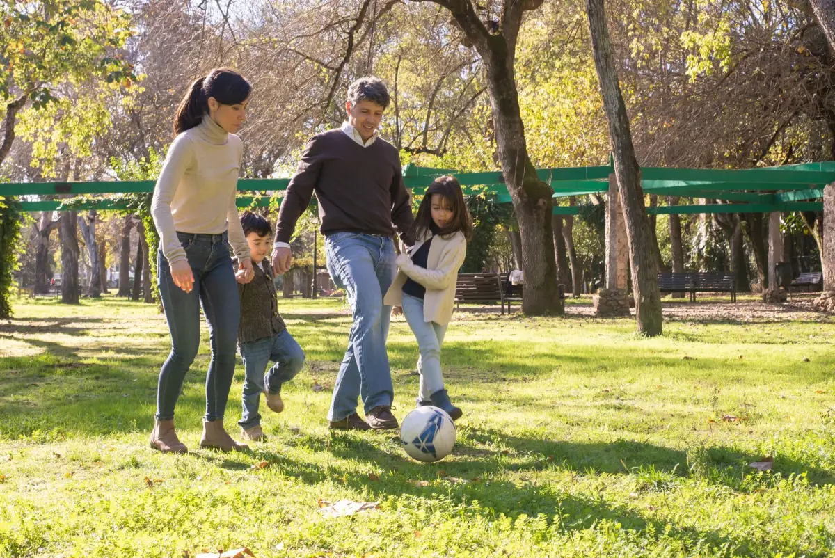 Parents and children playing football together in a park